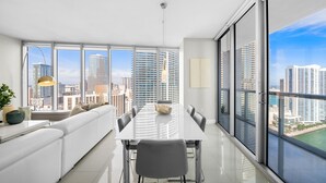 A modern living room with a dining area, large windows, and a city view. - ICON W BRICKELL LUXURIOUS OCEAN VIEW 2BR/2BA #3002 (Miami)