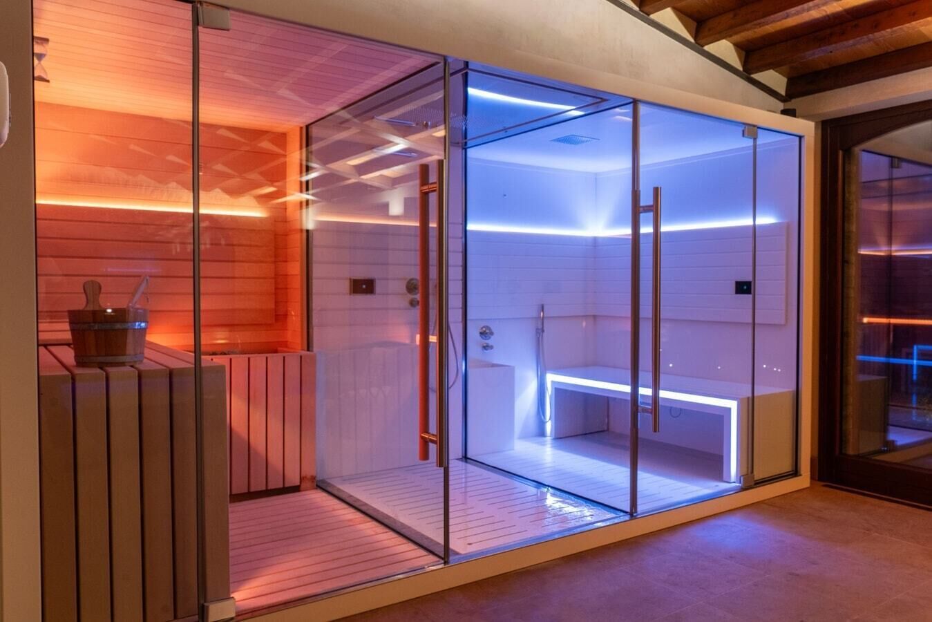 A modern sauna with glass walls, wooden benches, and a wooden floor.