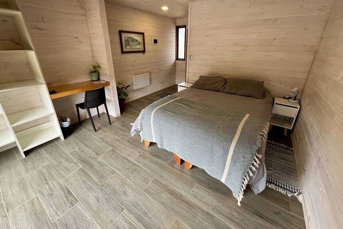 A bedroom with a bed, a desk, and a chair.