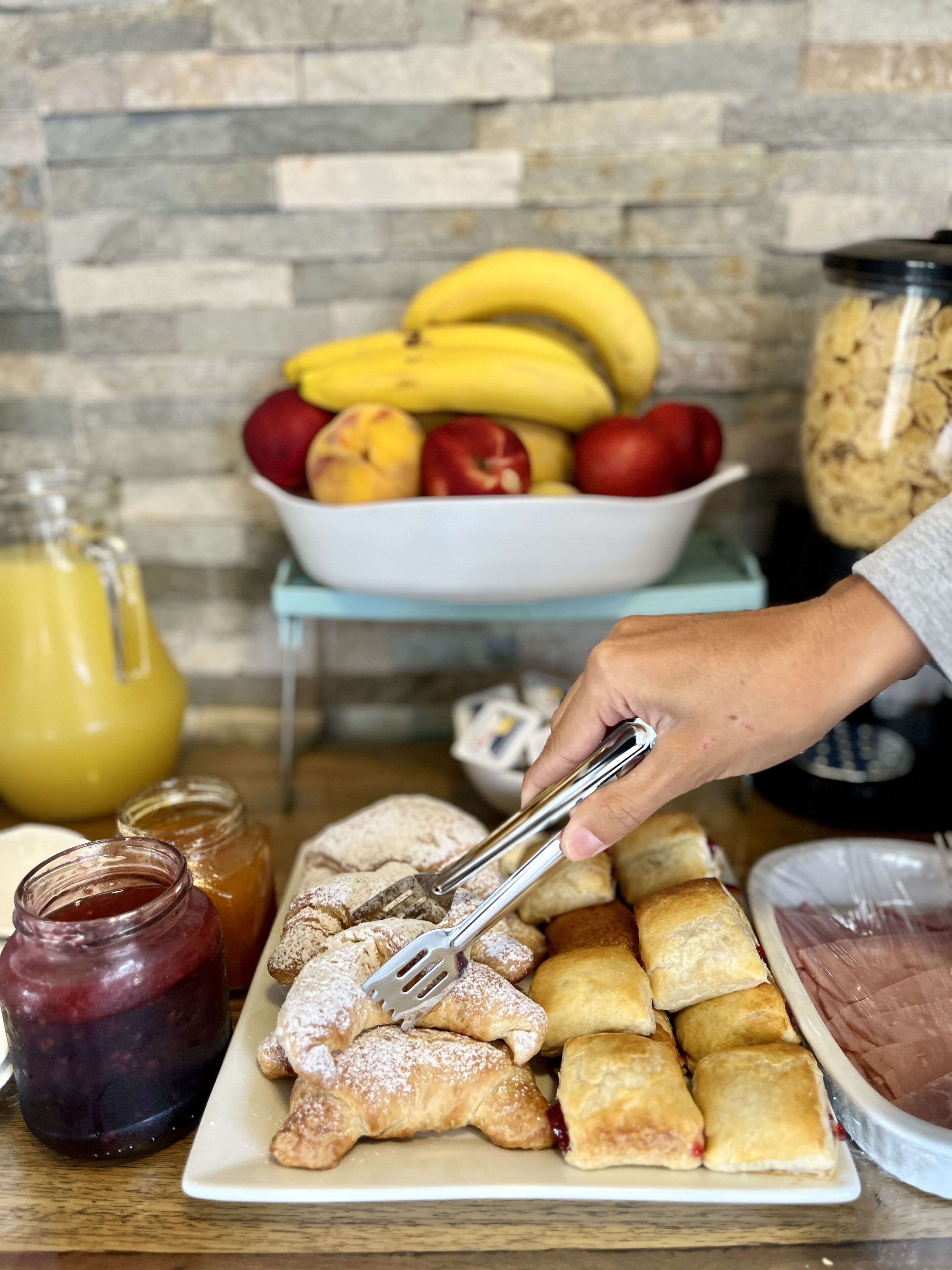 Un bufé de desayuno con bollería, frutas y salsas.