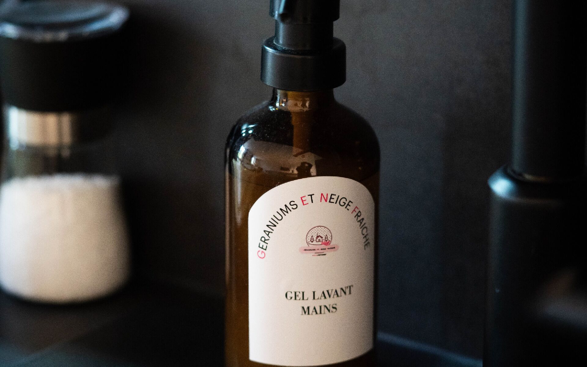 A bottle of gel with a label that reads "GERANIUMS ET NEIGE FRAICHT" and "GEL LAVANT MAINS".