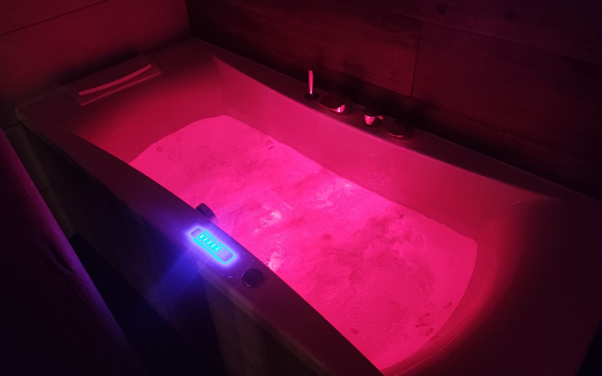 A bathtub with a blue light feature and a pink light.