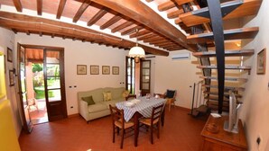 Un coin repas avec une table dressée pour quatre personnes, un canapé et un escalier.