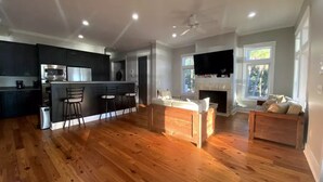 A spacious living area with hardwood flooring, a kitchen with dark cabinetry, a bar area, and a fireplace. - PRIVATE ISLAND - 110 Acres in SC (Okatie)