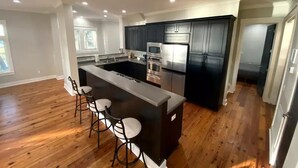 A modern kitchen with a central island, bar stools, and built-in appliances. - PRIVATE ISLAND - 110 Acres in SC (Okatie)