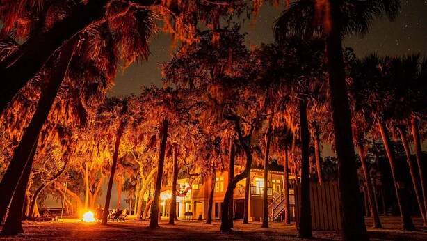 A well-lit building surrounded by tall trees at night. - PRIVATE ISLAND - 110 Acres in SC (Okatie)