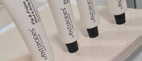 Four tubes of Antipodes hand and body lotion on a countertop.