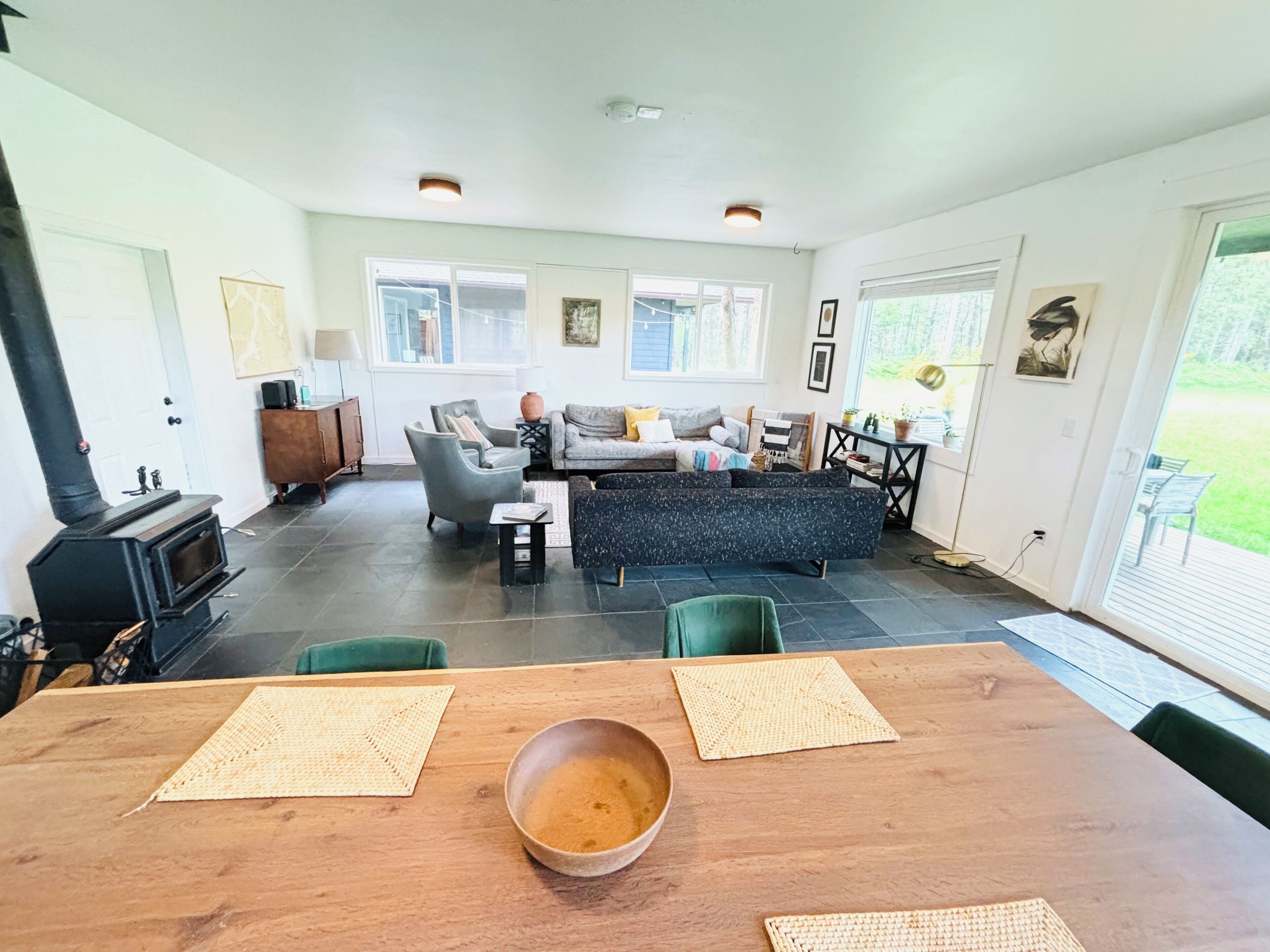 Een ruime woonkamer met een open haard, een zithoek en een eettafel met placemats.