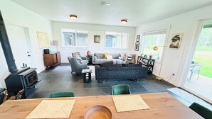 A spacious living area with a fireplace, a sofa set, and a dining table with placemats. - Forest Hideaway House with hot tub and trail (Shelton)