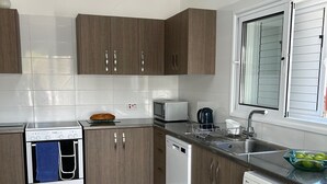 Ett modernt kök med träskåp, en diskho i rostfritt stål, en mikrovågsugn, en ugn och en tvättmaskin.