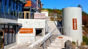 A hotel entrance with a sign reading "Island Inn," a staircase leading to the entrance, and a large cylindrical structure labeled "123" in the background.