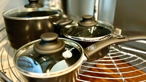 A kitchen with stainless steel pots and pans on a rack.