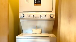 A white FRIGIDAIRE washer and dryer unit with a safety warning label and a cloth hanging on the dryer door.