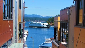 A narrow waterway with a large ferry in the distance, flanked by buildings with balconies overlooking the water.