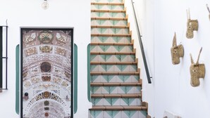 A staircase with a geometric pattern, a decorative door, and a wall with hanging items. - El traslado Alojamiento (Almonte)