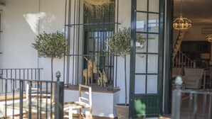 A sunlit room with a wooden bench, a small table, and a potted plant. - El traslado Alojamiento (Almonte)