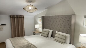 A neatly arranged hotel room with a large bed, a bedside table with a lamp, a decorative ceiling light, and a window with curtains. - El traslado Alojamiento (Almonte)
