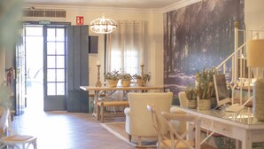 A dining area with a chandelier, a table with candles, and a mural on the wall. - El traslado Alojamiento (Almonte)