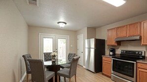 Una cocina compacta con nevera, estufa y armarios de madera.