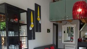 A compact living space with a dining table, a sofa, and a bookshelf filled with glassware.