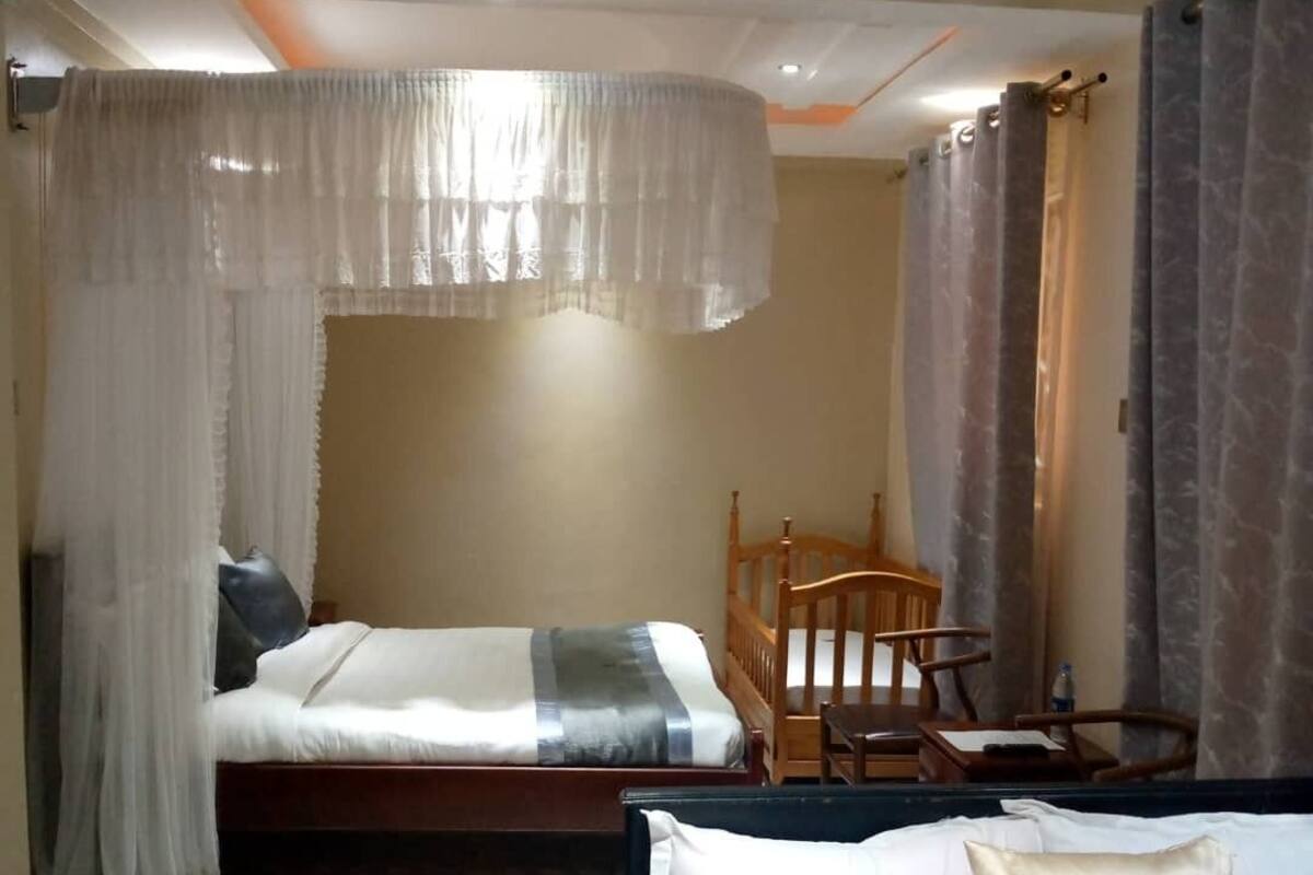 A bedroom with two beds, a wooden chair, and a small table.