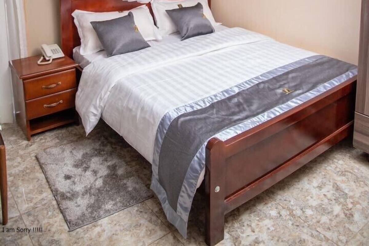A bedroom with a canopy bed, a bedside table with a phone, and a nightstand.