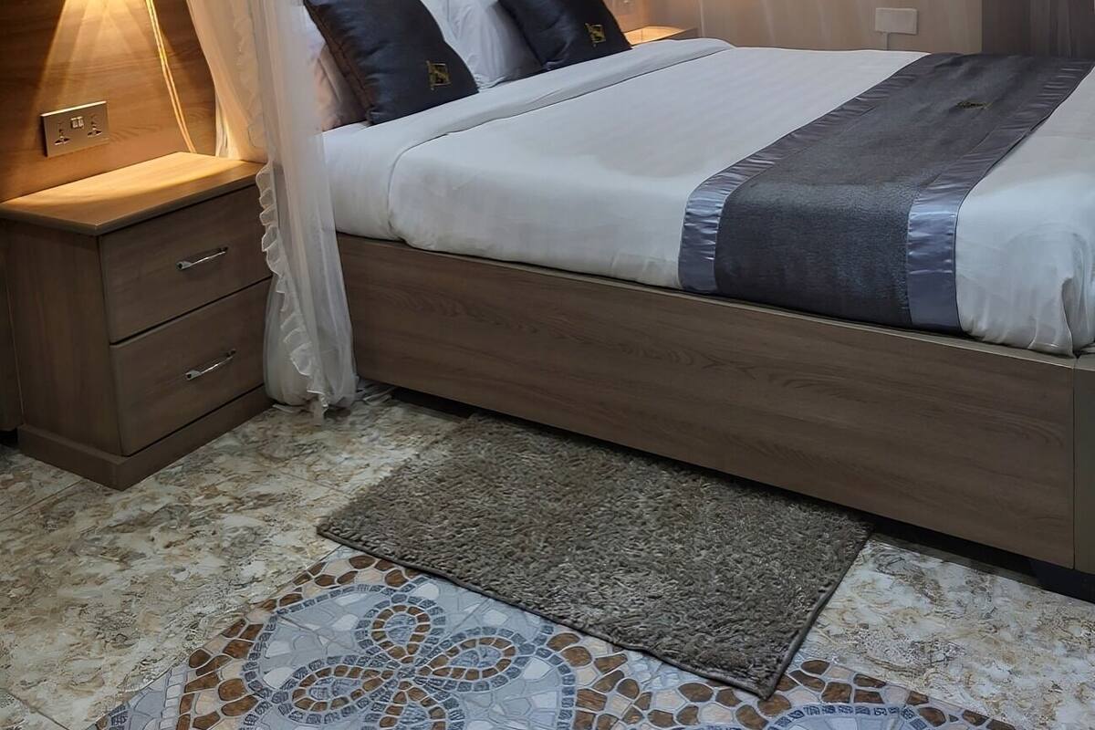 A bedroom with a canopy bed, bedside lamps, a nightstand, and a patterned rug.