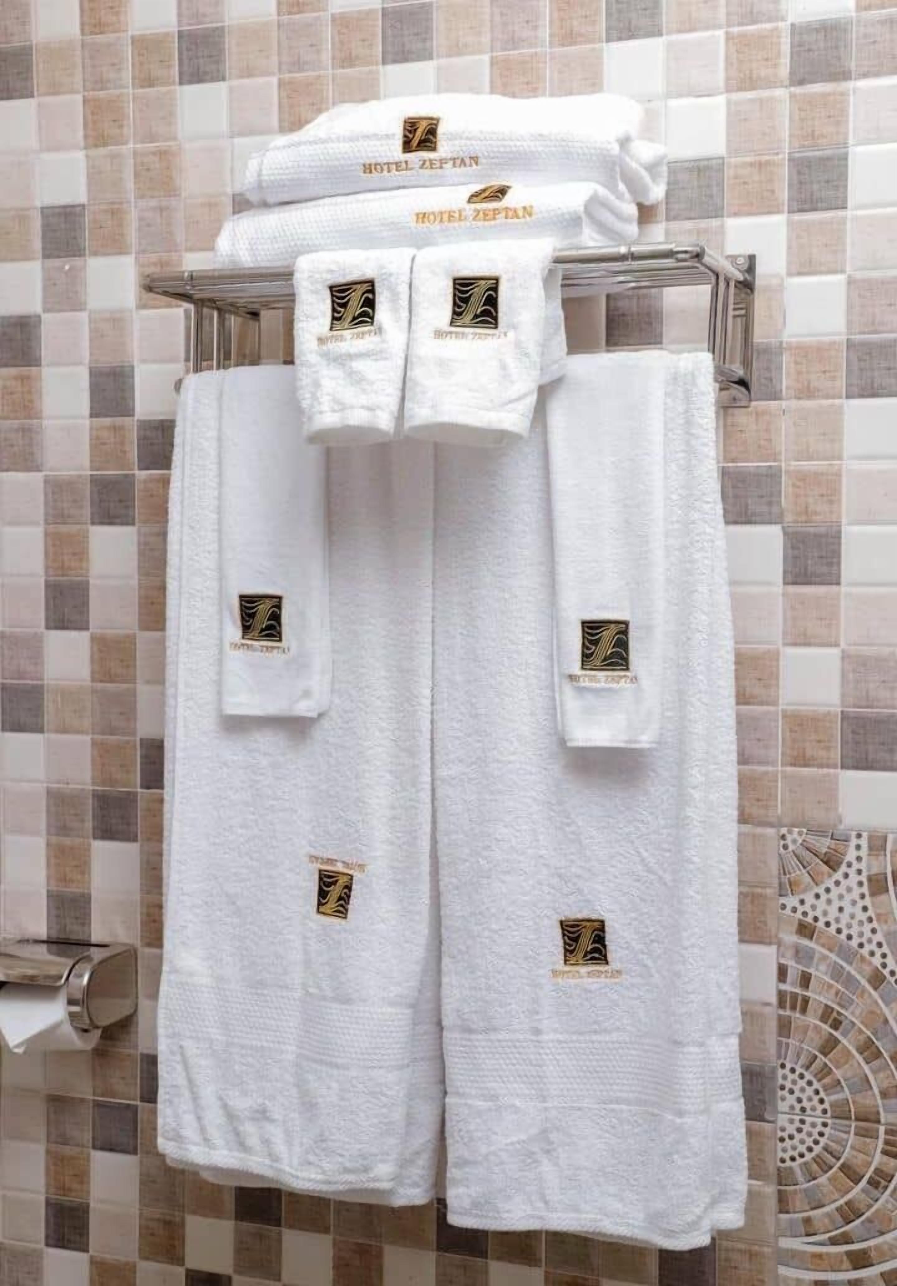Ein Badezimmer mit gefliesten Wänden, einem Handtuchhalter mit gefalteten Handtüchern und einem Toilettenpapierhalter.