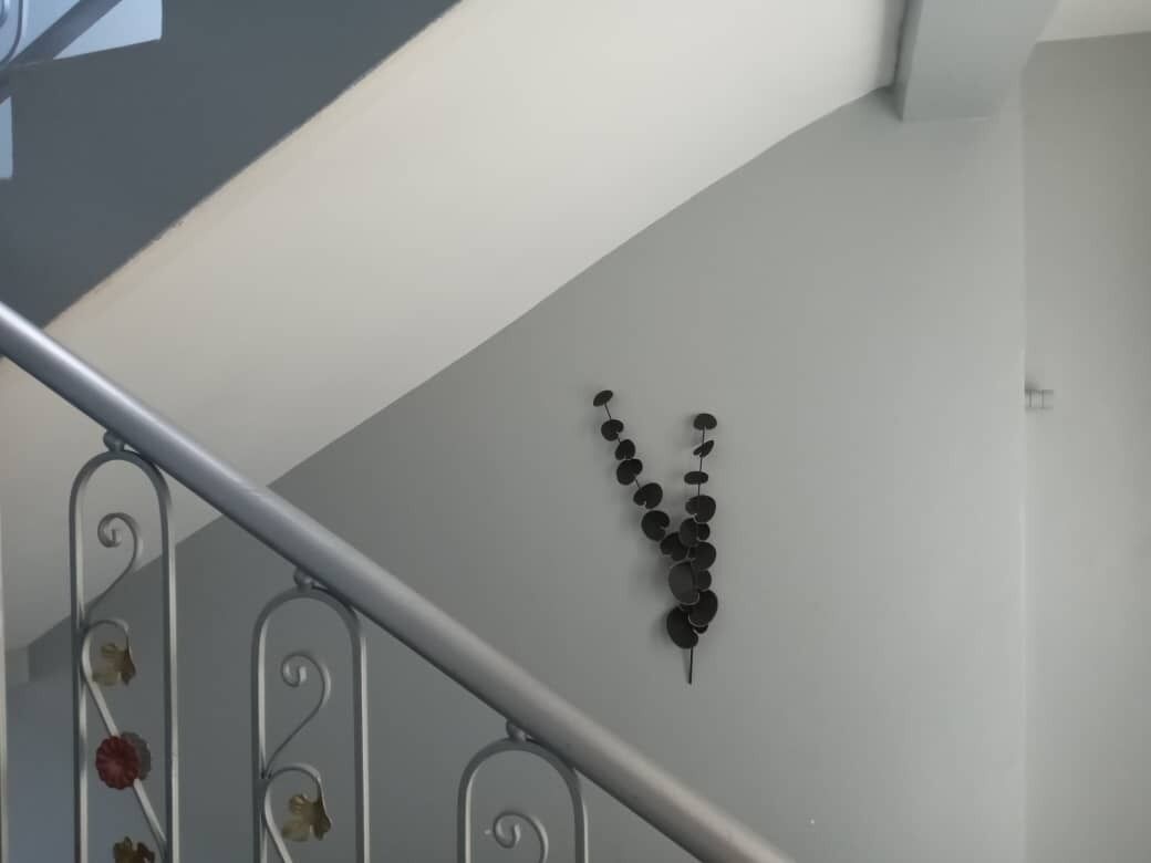 Eine Treppe mit Metallgeländer und einem an der Wand befestigten, dekorativen Element aus runden Objekten.