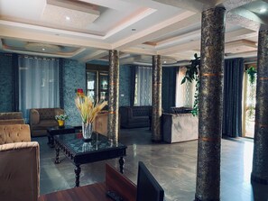 A spacious lobby with a high ceiling, decorative columns, and a mix of seating arrangements including sofas and armchairs. - Hotel Zeptan (Jinja)