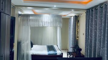 Un dormitorio con una cama, una mesita de noche, una silla y una ventana con cortinas.