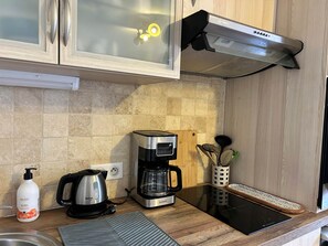 A kitchen with a coffee maker, a kettle, a bottle of soap, and a tablet on the counter.