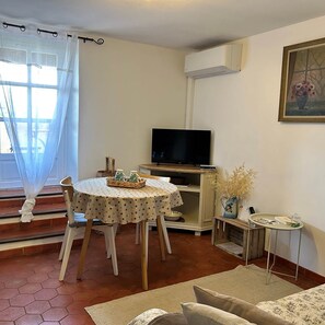 Ein Wohnzimmer mit einem runden Tisch, einem Fernseher und einem Gemälde an der Wand.
