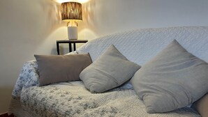 A bed with a floral-patterned quilt, a bedside lamp, and two pillows. - Gîte 2 Personnes Bruyère - 35 m² (Niozelles)