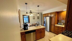A modern kitchen with wooden cabinets, stainless steel appliances, and a dishwasher. - Comfortable 3BR Home-Prime Video, WiFi, Parking (Schererville)