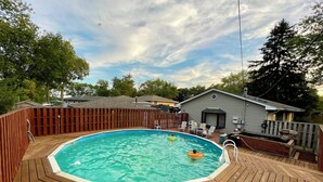 A swimming pool with a wooden deck, surrounded by a wooden fence, and a small building in the background. - Comfortable 3BR Home-Prime Video, WiFi, Parking (Schererville)