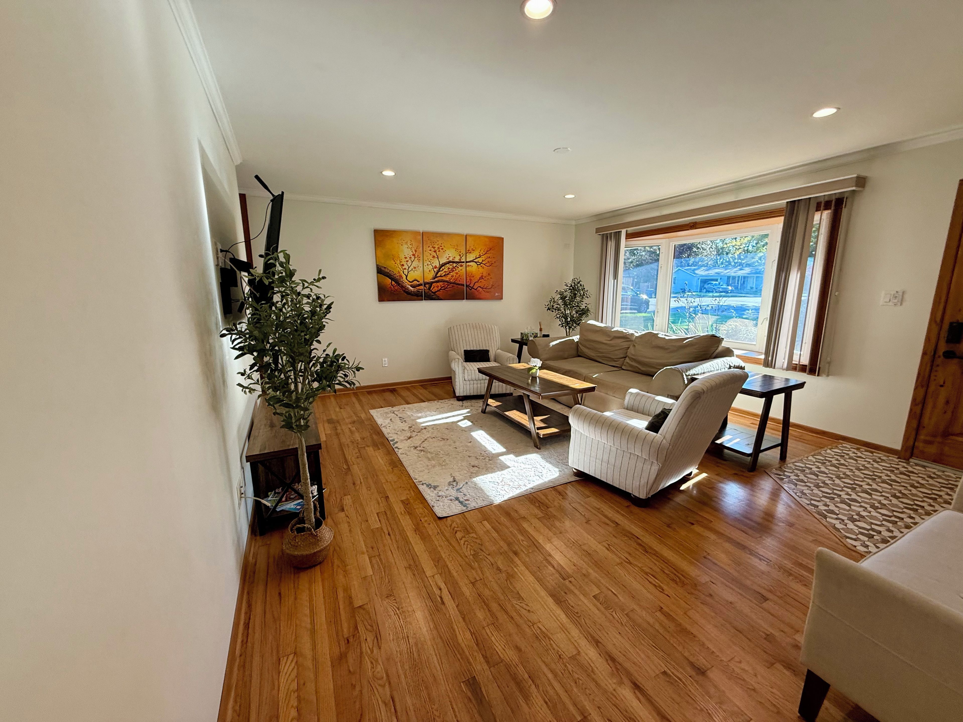 A modern living room with a sofa, armchairs, a coffee table, and a large window with a view.