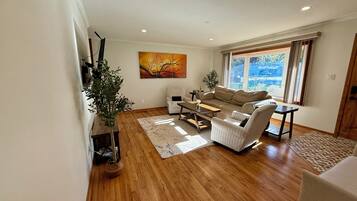A modern living room with a sofa, armchairs, a coffee table, and a large window with a view.