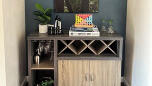 Une console en bois sur laquelle sont posés un tableau encadré représentant un chien grimpant à un arbre, une plante et un jeu de société.