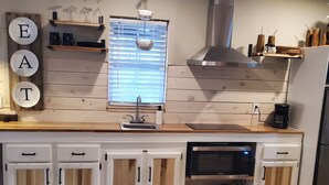 Ett modernt kök med vita skåp, en inbyggd mikrovågsugn och en kaffebryggare.