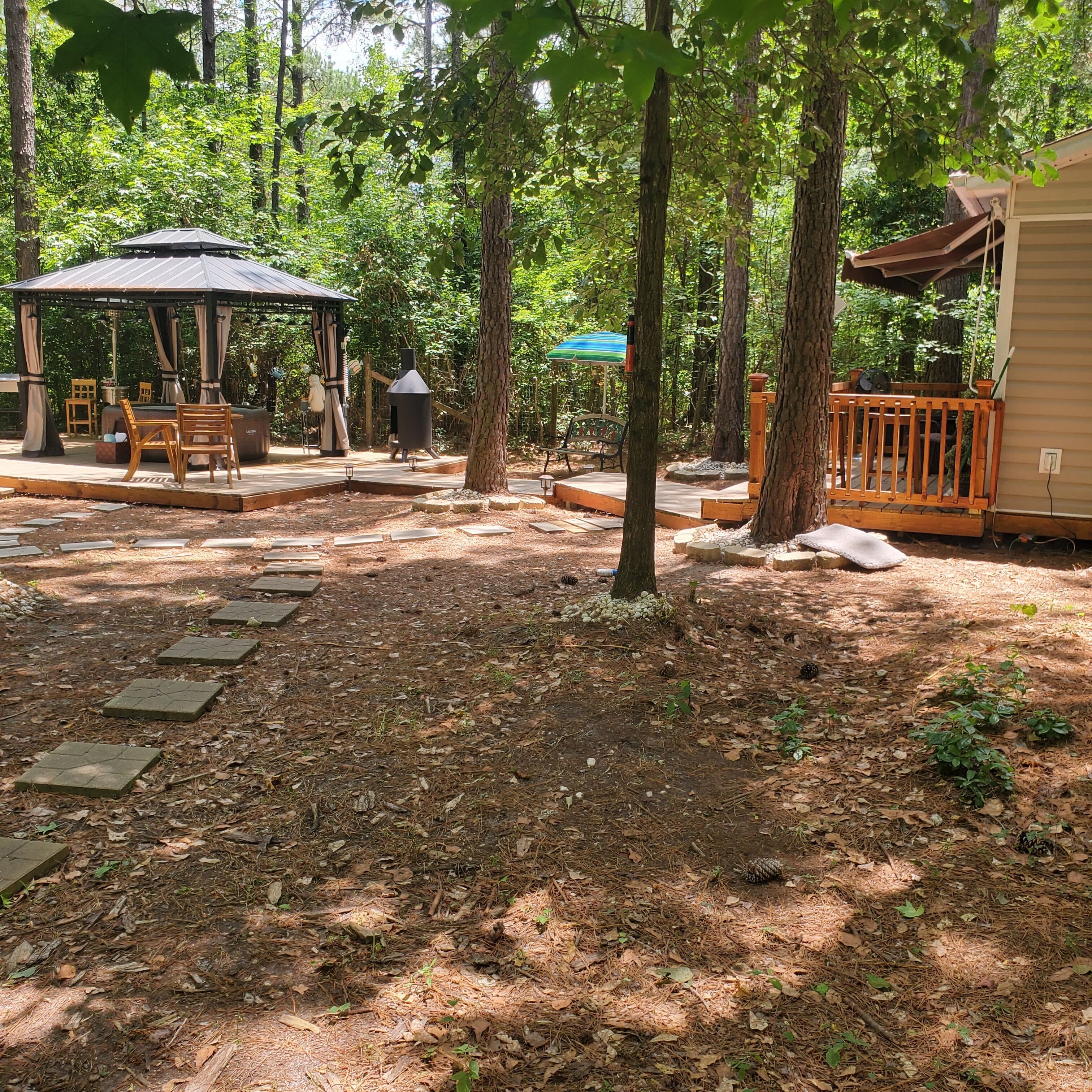 A covered outdoor seating area with a gazebo, picnic tables, and a barbecue grill.