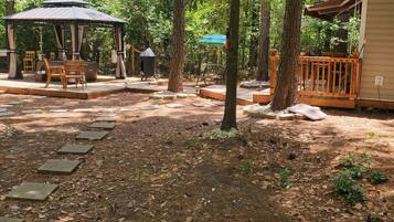 A covered outdoor seating area with a gazebo, picnic tables, and a barbecue grill.