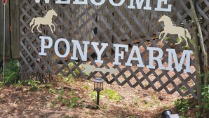 En träskylt med texten ”VÄLKOMMEN TILL PONYGÅRDEN” och silhuetter av hästar.