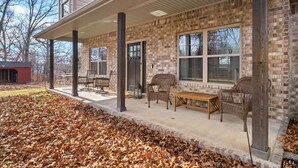A covered patio with wicker furniture and a brick exterior.