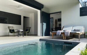 Uma área moderna com piscina externa, espreguiçadeiras e uma mesa de jantar.