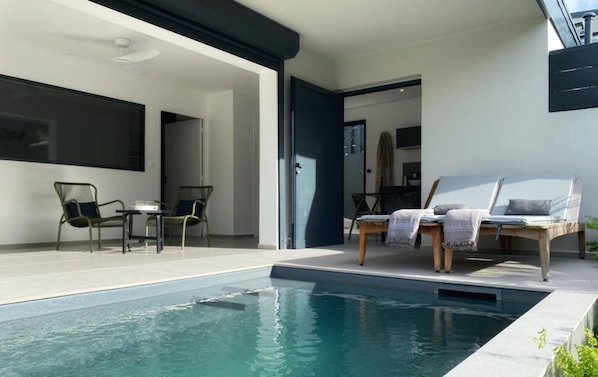 A modern outdoor pool area with lounge chairs and a table.