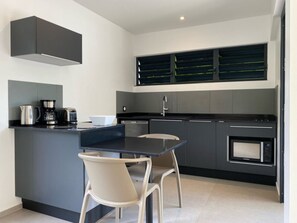 A modern kitchen with a central island, two chairs, a coffee maker, and a microwave.