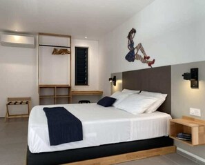 A modern bedroom with a bed, bedside tables, a wardrobe, and a wall-mounted light fixture.