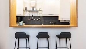 Eine moderne Küche mit einem großen Spiegel über einer Bar, inklusive Herd, Spüle und hängenden Kochutensilien.