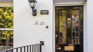 Un bâtiment blanc avec une porte noire, un lampadaire et une enseigne indiquant « Walsingham House, n° 20 ».